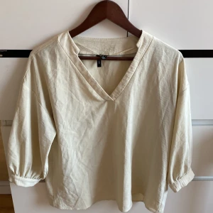 Beige trekvartsärmad blus från Vero Moda - Säljer en beige blus från Vero Moda med v-ringning och trekvartsärmar. Blusen har en avslappnad passform och är perfekt för både vardag och lite finare tillfällen. Tillverkad i ett mjukt och bekvämt material. Köpt för 350kr