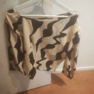Mönstrad topp från Shein - Säljer en snygg topp från Shein med ett unikt svart och beige mönster. Perfekt för att sticka ut i mängden. Toppen har en lös passform och är tillverkad i ett lätt material.