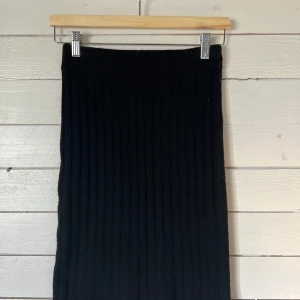 Svart ribbad kjol från Pieces - Snygg svart ribbad kjol från Pieces. Kjolen har en liten slits baktill som ger en snygg detalj.