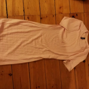 Ljusrosa ribbad klänning från H&M Divided - Säljer en ljusrosa ribbad klänning från H&M Divided. Klänningen har korta ärmar och en enkel, stilren design som passar perfekt för både vardag och fest. Den är gjord i ett mjukt och bekvämt material.