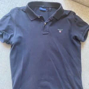 Mörkblå pikétröja från GANT - Säljer en stilren mörkblå pikétröja från GANT. Skit nice till sommaren. Skick: 9/10. Nypris: 900kr. Säljer pga växt ur storleken. Skriv vid minsta funderingar🙏🏼