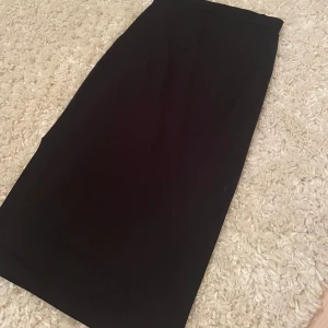 Svart kjol med slits - Snygg svart kjol med en elegant slits på sidan. Perfekt för en stilren look. Kjolen har en klassisk design som passar till många olika tillfällen. Säljer då den är för liten. Skriv privat för fler bilder