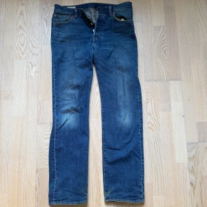 Blå 501 jeans från Levi's - Klassiska blå 501 jeans från Levi's med en rak passform. De har en knappgylf och femficksdesign. Perfekta för en avslappnad stil. Storlek W30 L32