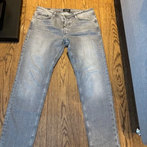 Grå jeans från Jack & Jones - Säljer ett par grå jeans från Jack & Jones i modellen 'Glenn Original'. Jeansen har klassisk femficksdesign, dragkedjegylf och raka ben. Perfekta för dig som gillar en stilren och enkel look.