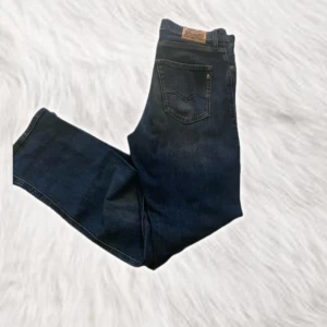Mörkblå jeans från Replay - Snygga mörkblå jeans från Replay med klassisk femficksdesign. De har en dragkedja och knapp framtill. Perfekta för en stilren look. 