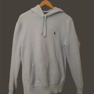 Ralph lauren Hoodie - Säljer en ljusblå hoodie från Ralph Lauren med klassisk broderad logga på bröstet. Tröjan har huva med dragsko och en stor magficka. Perfekt för en avslappnad stil.