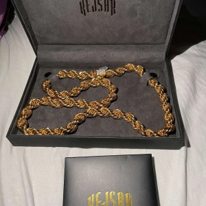 Guldfärgat kedjehalsband från Kejsar - Säljer ett snyggt guldplaterad halsband från Kejsar med tvinnad kedja och glittrigt spänne. Kommer i original ask med logga. Perfekt accessoar för att lyfta din stil. 65cm lång med 10mm bredd på kedjan köpt för 2700kr 