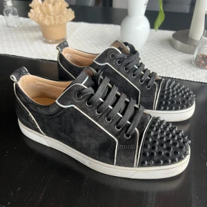 Louboutin sneaker - Louboutin skor. Svart färg med vit outline och spikar. 1 spik på vänster och 5 på höger saknas, tycker dock att man knappt ser det faktiskt. Storlek 41! Lite slitage på utsidan av skor efter tvätt. Sjukt unika så var snabb på att fynda!