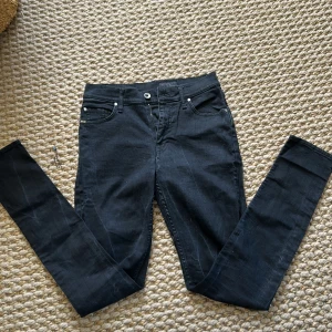 Svarta jeans från Tiger of Sweden - Säljer ett par svarta  jeans från Tiger of Sweden, modell Kelly. Klassisk femficksdesign med dragkedja och knapp framtill. Snygg passform och stilren look, perfekta till många outfits.