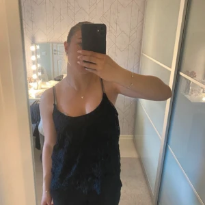 Svart spetslinne från Gina Tricot - Säljer ett svart linne från Gina Tricot med tunna axelband och vacker spets över hela toppen. Perfekt att styla till olika outfits och ger en elegant känsla. Linnet är lätt och har en feminin look.