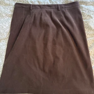 Brun kjol från Cappuccini - Brun vintage kjol från Cappuccini med klassisk rak passform och hällor i midjan köpt på secondhand. Storlek 46, men något stor på mig som vanligtvis har 40/42. Kjolen har dragkedja och knapp på sidan samt en liten ficka med dragkedja bak. Hör av dig om du har frågor eller förslag på pris💕