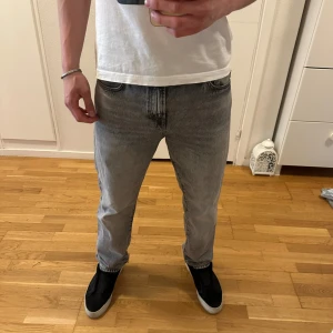 Grå jeans från BOSS (ny skick)  - Säljer ett par grå jeans från BOSS med klassisk femficksdesign och svart BOSS-lapp bak i midjan. Jeansen har en rak passform och är tillverkade i denim med en lätt tvättad look. Perfekta för en stilren vardagsoutfit.