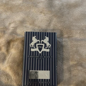 Parfums de Marly Layton Royal Essence Eau de Parfum - Exklusiv herrparfym från Parfums de Marly, Layton Royal Essence. Flaskan är matt mörkblå med silverdetaljer och har en elegant, lyxig design. Doften är intensiv och sofistikerad, perfekt för dig som vill sticka ut. Locket är lite loss men funkar perfekt 
