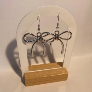 Silverfärgade örhängen i rosettform - Säljer ett par snygga silverfärgade örhängen formade som rosetter. Perfekta för att ge din outfit en söt och trendig touch. Lätta att bära och funkar till alla tillfällen!