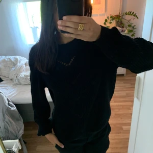 Svart stickad tröja från VILA - Säljer en svart stickad tröja från VILA i storlek M. Tröjan har ett snyggt mönsterstickat parti framtill och långa ärmar. Perfekt för kyligare dagar och enkel att matcha med olika outfits.