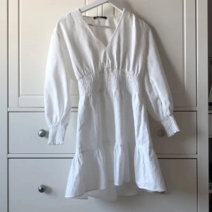 Vit Zara klänning  - Säljer en vit klänning från Zara med v-ringning och långa ärmar. Perfekt för sommarens alla tillfällen!