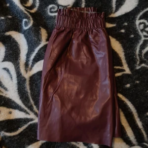 Vinröd kjol i skinnimitation från ONLY! - Säljer en vinröd kjol i skinnimitation från ONLY med bred resår i midjan. Kjolen är snyggare på, är skön och har fickor. Skulle säga att den även passar stl38. Lite skrynklig efter att ha legat nerpackad. En tvätt gör nog susen för det.