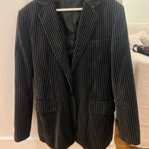 Svart och grå randig kavaj från Selected - Säljer en svart och grå randig kavaj från Selected. Kavajen har klassisk passform med smala slag, tre fickor framtill och innerficka med knapp. Den är ca i storlek M