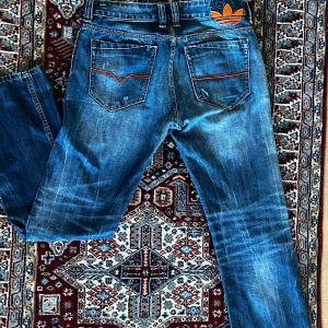Blå Diesel Viker-AD jeans - Feta unika blå jeans från diesel och adidas med den klassiska femficks designen, jeansen har coola slitningar med knappgylf. Personligen tycker jag jeansen ger av en cool aura och anledning till att jag säljer är för dem är för små på mig