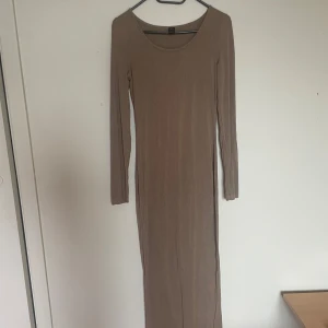 Beige långklänning från SHEIN - En stilren beige långklänning från SHEIN med rund halsringning och långa ärmar. Klänningen har en tight passform och är tillverkad i ett mjukt, stretchigt material som sitter snyggt längs kroppen.🤎