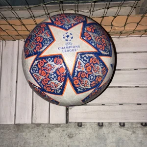 Adidas Champions League fotboll - Champions League fotboll från Adidas i storlek 4. Bollen är vit med blå och orange detaljer i ett unikt mönster och stora stjärnor. Tillverkad i slitstarkt syntetmaterial och perfekt för matcher eller träning. Officiell Champions League-design.