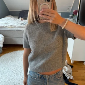 Grå stickad topp från Zara - Supermjuk grå stickad tshirt från Zara med korta ärmar och rund halsringning. Jätteskönt material och i bra skick. Lite liten i storleken☺️