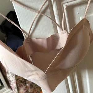 Ljusrosa bandeau topp från Magic - Supersnygg ljusrosa bh topp från Magic med tunna axelband och slät, mjuk yta. Toppen har en clean look som passar perfekt under det mesta.  Endast provad pga för liten för mig så jättebra skick. Storlek S