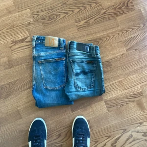 2 par blå Nudie Jeans, stl 24/30 & 25/28 - Säljer två par klassiska blå jeans från Nudie Jeans i storlek 24/30 och 25/28. Båda har snygg tvätt med slitningar och kontrastsömmar, klassiska bakfickor och orange detaljer. Perfekta för dig som gillar en tidlös jeanslook. Passar 152/146 jag e 155 o lite fett o dom e lite tajta 