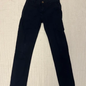 Mörkblå chinos från Hampton Republic - Snygga mörkblå chinos från Hampton Republic i storlek 164. Klassisk rak passform med knapp och dragkedja framtill samt fickor både fram och bak. Perfekta för en clean och stilren look.