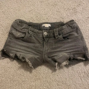 Grå jeansshorts från gina young - Snygga grå jeansshorts från gina young med fransig kant längst ner, klassisk femficksmodell och knappstängning. Baksidan har två fickor med lock och knapp.💞💞