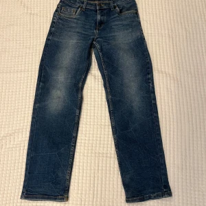Levi's Loose Taper blå jeans - Säljer ett par blå Levi's Loose Taper jeans med klassisk femficksdesign och snygga slitningar. Jeansen har en loose fit upptill och smalnar av nedtill för en modern look. Perfekta för dig som gillar avslappnad stil med lite edge.
