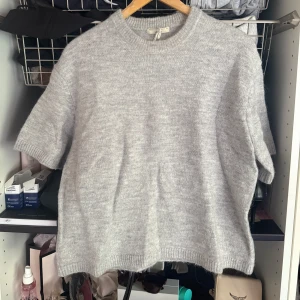 Grå stickad T-shirt från Gina Tricot - Supermysig ljusgrå stickad tröja från Gina Tricot med korta ärmar och rund hals. Storlek M men passar S också. Ingen prislapp kvar men är i princip oanvänd. 
