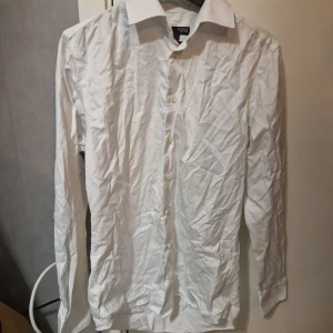 Vit skjorta Dressmann Egyptian Cotton M - Klassisk vit skjorta från Dressmann i egyptisk bomull. Skjortan har lång ärm, knappar framtill och en stilren krage. Perfekt för dig som vill ha en clean och tidlös look. Passar till många olika outfits och är riktigt skön tack vare bomullsmaterialet.