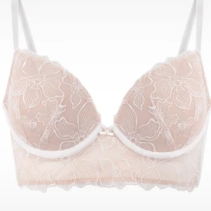 Blommig spets bralette från Hunkemöller - Superfin bralette Bh från Hunkemöller i beige med vita blommiga spetsdetaljer. Axelbandsmodell med justerbara band och hakknäppning bak. Perfekt för dig som gillar romantiska och feminina detaljer. Storlek 75D enligt lappen.