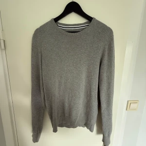 Grå stickad tröja från Pier One - Snygg grå stickad tröja från Pier One med rund hals och ribbade muddar vid ärmslut och nederkant. Knappt använd, har inga defekter 