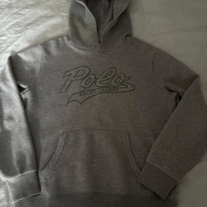 Grå hoodie från Polo Ralph Lauren - Snygg grå hoodie frå Polo Ralph Lauren , bra skick förutom vid slutet av armarna se sista bild men inget man lägger märkte till så mycket  14-16 år eller xs