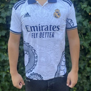 Real Madrid vit drakmönstrad fotbollströja - Stilren concept Real Madrid tröja i nyskick.  																																																																																																														Nypris:500kr GORILLAPRIS:350kr                     Skick:9/10                               KVITTO MEDKOMMER!