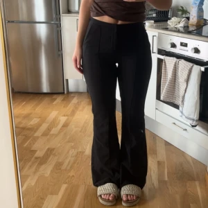 Svarta bootcut kostymbyxor - Snygga svarta kostymbyxor med bootcut passform och medhögmidja. Pressveck i mitten och en fuskficka där bak. Använda men ej något problem med dom. Inger som är sönder eller liknande