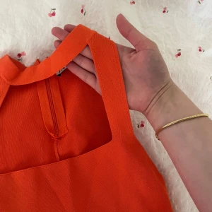 Orange topp med utskärning  - Säljer denna super fina orangea topp med utskärning i ett tjockare material med dragkedja i nacken för att kunna få på dig toppen lättare. Knappt använd och i oanvänt skick 