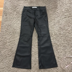Skinn byxor från bershka  - Snygga svarta byxor från Bershka i skinnimitation med bootcut-ben och hög midja. Byxorna har släta fickor fram och en dekorativ ficka bak. Perfekta för en edgy och trendig look.