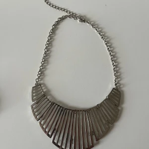 Halsband  i silverfärg - Halsband i silverfärgad metall med geometriskt, solfjäderformat hänge.