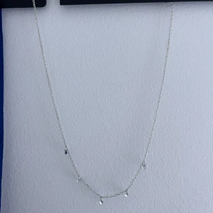 Silvrigt halsband med små pärlor - Snyggt och tunt halsband i silverfärgad metall med fem små, runda pärlor som hänger längs kedjan. Perfekt för dig som gillar minimalistisk och stilren design. Kedjan är enkel och pärlorna ger en subtil touch av bling.