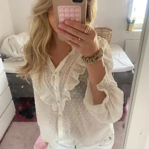 Vit volangblus från Zara💝💝 - Supersöt vit blus med volanger och prickigt mönster. Blusen har transparent tyg, knappar framtill, v-ringning och långa ärmar med smock vid ärmslut. Perfekt för dig som gillar romantiska detaljer och en luftig känsla.