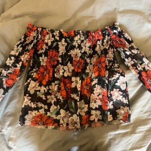 Blommig offshoulder topp Gina Tricot - Supersöt offshoulder topp från Gina Tricot i storlek XS. Topp med blommigt mönster i svart, rött, vitt och grönt. 