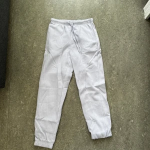 Ljusgrå mjukisbyxor från Pigalle - Ljusgrå mjukisbyxor från Pigalle i storlek XS. Byxorna har resår och snörning i midjan samt muddar vid bensluten. Tillverkade i mjukt bomullsmaterial med fleece på insidan för extra komfort. Perfekta för chill dagar eller när du vill vara bekväm.