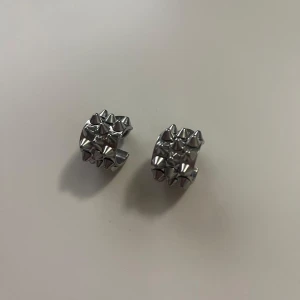 Silvriga örhängen med nitar/. EDBLAD - Coola silvriga örhängen med rund form och tydliga nitar runt hela ytan. Perfekta för dig som vill ha en edgy och unik accessoar till din stil.