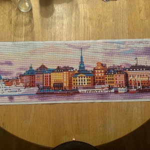Diamond painting av Stockholms stadssilhuett - Säljer en färgglad diamond painting som föreställer Stockholms stadssilhuett med klassiska byggnader och båtar. Tavlan har många detaljer och skimrande stenar i olika färger, perfekt för att dekorera väggen med en unik touch.