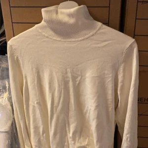 Vit polotröja - Klassisk vit polotröja med lång ärm och hög krage. Perfekt att styla lager på lager eller bära som den är. Mjuk och skön känsla, passar till många olika outfits.