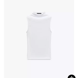 Vit ärmlös polotopp från zara  - Säljer en stilren vit ärmlös polotopp med hög hals. Toppen har en tight passform och är perfekt att styla till olika outfits. Den e vit de va annan färg på tröjan på model hade på sig den,helt ny säljer för den inte va min still.