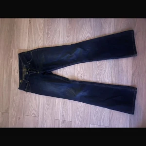 Mörkblå bootcut jeans från Lee - Mörkblå jeans från Lee med klassisk bootcut passform. Jeansen har fem fickor och Lee-lapp bak i midjan. 